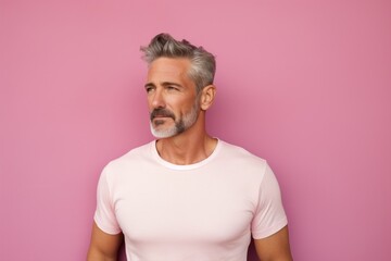 Portrait of a content man in his 40s donning a trendy cropped top against a solid pastel color...