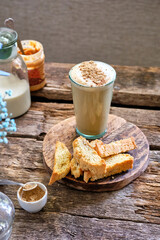 still life with a cappuccino and biscotti on a wooden table.