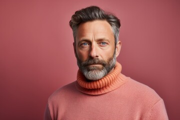 Obraz premium Portrait of a content man in his 40s dressed in a warm wool sweater against a solid pastel color wall. AI Generation
