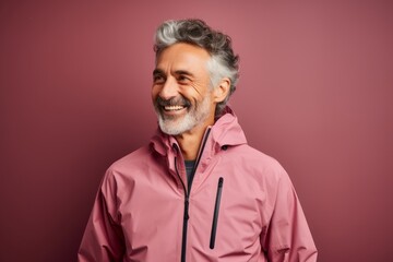 Obraz premium Portrait of a smiling man in his 60s wearing a windproof softshell against a solid pastel color wall. AI Generation