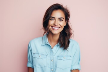 Portrait of a blissful woman in her 20s sporting a versatile denim shirt against a solid pastel...