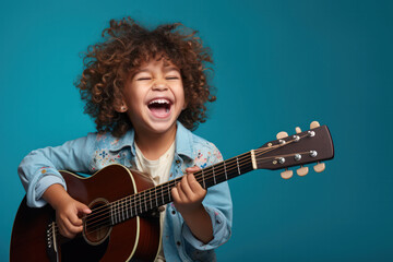 Obraz premium Musical Delight, Happy Child Strumming a Guitar with Joy on Blue Background