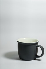 An empty dark grey real mug isolated on white background with clear and natural texture for background. Artistic shading of porcelain or ceramic mug.