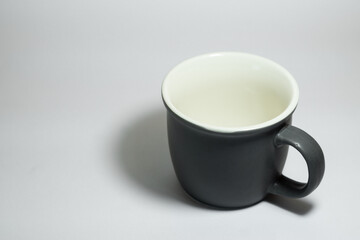 An empty dark grey real mug isolated on white background with clear and natural texture for background. Artistic shading of porcelain or ceramic mug.