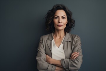 Obraz premium Portrait of a tender woman in her 40s wearing a chic cardigan against a blank studio backdrop. AI Generation
