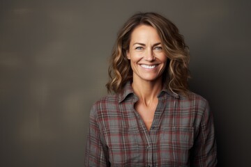 Fototapeta premium Portrait of a happy woman in her 40s wearing a comfy flannel shirt against a blank studio backdrop. AI Generation