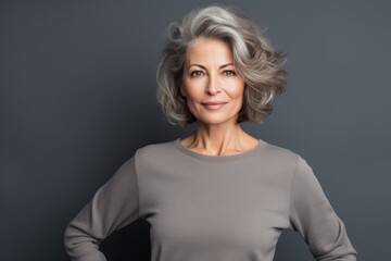 Portrait of a tender woman in her 50s showing off a thermal merino wool top against a blank studio backdrop. AI Generation