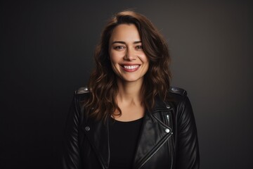 Fototapeta premium Portrait of a smiling woman in her 30s sporting a classic leather jacket against a light wood minimalistic setup. AI Generation
