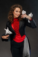 A portrait of a magician in a magician's costume and black top hat performing magic tricks with white doves against a dark background