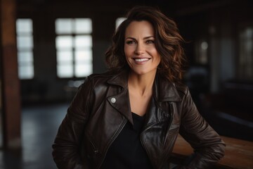 Portrait of a smiling woman in her 40s sporting a classic leather jacket against a empty modern loft background. AI Generation