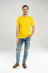 Obraz premium Full length portrait of happy handsome young man in yellow t-shirt isolated on white background.