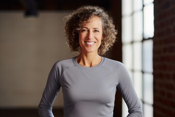 Portrait of a grinning woman in her 50s showing off a lightweight base layer against a empty modern loft background. AI Generation