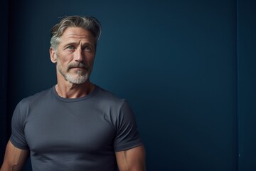 Fototapeta premium Portrait of a content man in his 50s sporting a technical climbing shirt against a bare monochromatic room. AI Generation