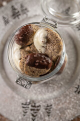 Homemade christmas cookies with poppy seeds and glazed chocolate in a glass jar on a silver plate