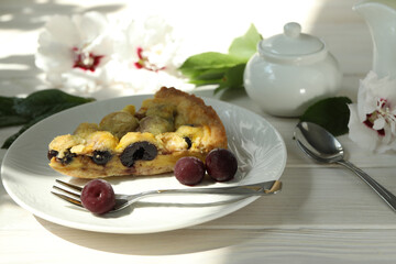 Delicious Quiche pie with cherry filling on white plate with cup of coffe. White wooden background