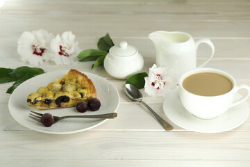Delicious Quiche pie with cherry filling on white plate with cup of coffe. White wooden background