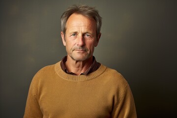 Fototapeta premium Portrait of a tender man in his 50s wearing a cozy sweater against a plain cyclorama studio wall. AI Generation