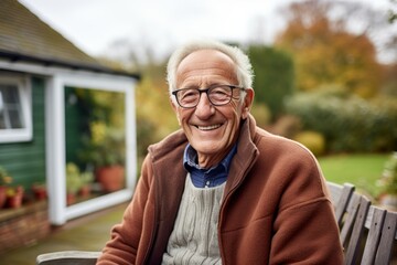 Obraz premium Portrait of a smiling man in his 80s dressed in a warm wool sweater against a crisp minimalistic living room. AI Generation