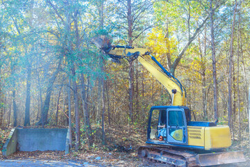 Builder uproots trees in forest with tractor so that land can be prepared for construction