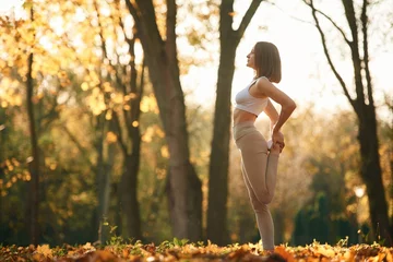 Fototapeten Fitness warm up exercises. Young beautiful woman is doing yoga in the autumn park © standret