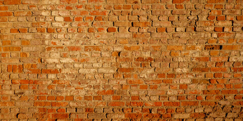 An orange brick wall with gray mortar, showing signs of age.