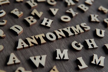 Closeup image of text ANTONYMS surrounded by scattered alphabet. - obrazy, fototapety, plakaty