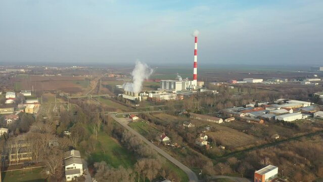 Above view, dolly move forwards, thermal power plant with smokestack and cooling towers. White smoke is coming out from chimney in production process of district heating, environmental pollution.