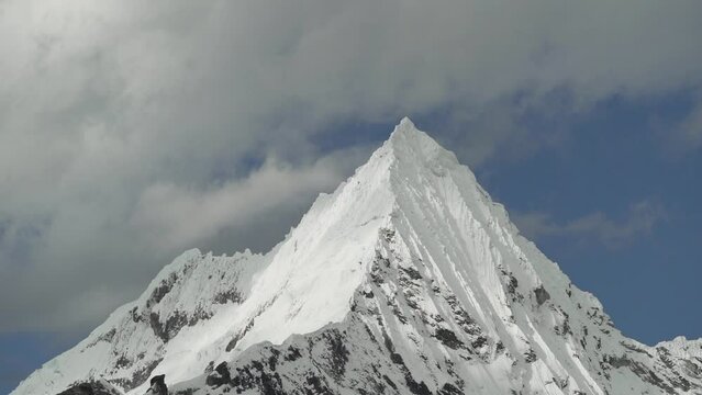 ice covered glacier of a pyramid shaped mountain at laguna paron lagoon in the high andes mountains of the cordillera blanca at huascaran, Peru, with snow covered mountain peaks on a bright sunny day.