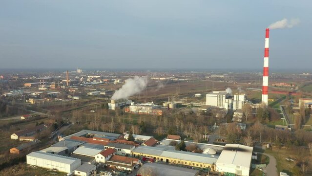 Above view, dolly move orbit, thermal power plant with smokestack and cooling towers. White smoke is coming out from chimney in production process of district heating, environmental pollution.