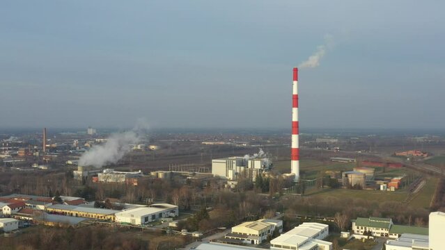 Above view on industrial landscape, thermal power plant with smokestack and cooling towers. White smoke is coming out from chimney in production process of district heating, environmental pollution.