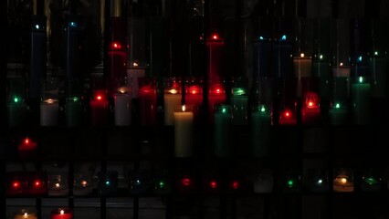 Burning colorful votive candles in a dark church in Barcelona, Spain