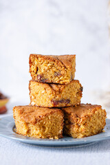 a pile of stacked slices of brown sugar cashew blondies, a vegetarian and vegan dessert with dates, dried fruits on a white background table and plate