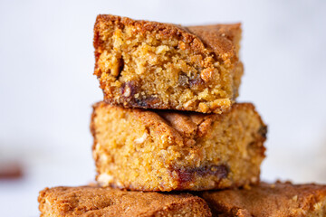 a pile of stacked slices of brown sugar cashew blondies, a vegetarian and vegan dessert with dates, dried fruits on a white background table and plate