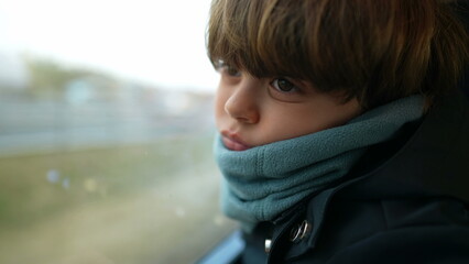 introspective contemplative child traveling by train leaning on window staring at scenery pass by...