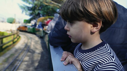 Observant Child Enjoying View, Leaning from Moving Miniature Train Wagon at Swiss Vapeur Park