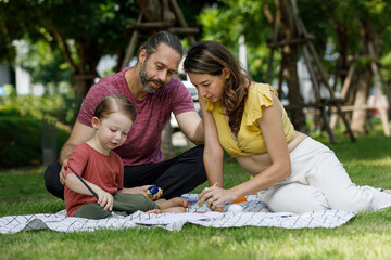 Happy family day, father, mother, son, Caucasian enjoying watercolor painting and picnic in nature.
