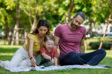 Happy family day, father, mother, son, Caucasian enjoying watercolor painting and picnic in nature.