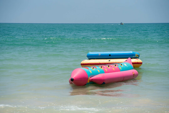 Colorful inflatable boats for playful beach sport close to seashore line, anchored at tropical sea, close up photo