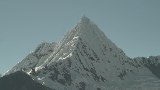 ice covered glacier of a pyramid shaped mountain at laguna paron lagoon in the high andes mountains of the cordillera blanca at huascaran, Peru, with snow covered mountain peaks on a bright sunny day.