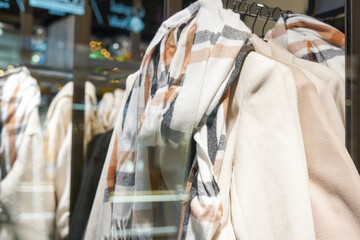 Women's autumn coat behind the glass in the store for sale. Classic women's fashion clothes. Autumn fashion collection