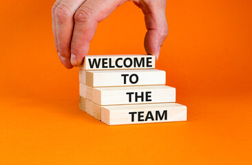Welcome to the team symbol. Concept words Welcome to the team on wooden block. Beautiful orange table orange background. Businessman hand. Business, motivational and welcome to the team concept.
