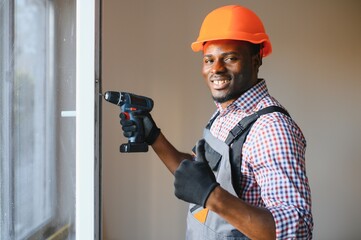 handsome young african american man installing bay window in new house construction site