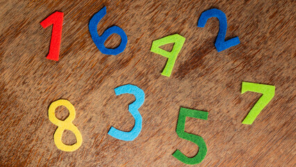Colorful felt numbers on wodden desk | top view