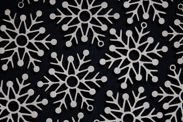 Pattern of wooden snowflakes on a black background, top view. Christmas and New Year.