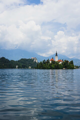 tiny island with church tower and nature in the middle of gorgeous clear water blue lake 