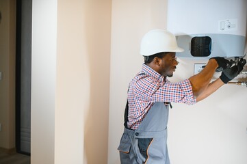 African american worker set up central gas heating boiler at home - obrazy, fototapety, plakaty