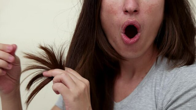 millennial woman brushing hair with wooden comb,looking at split ends,amazed shocked face. hand in surgical glove,doctor or medical assistant examining scalp and threads.double sided table mirror