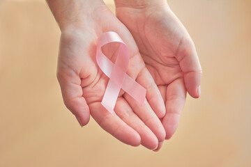 woman hand holding pink ribbon, a breast cancer symbol