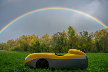 A Velomobile in light rain framed by a rainbow