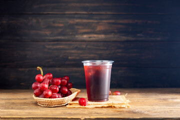 Red grape juice plastic glass With a bunch of grapes, fruit, food, natural sweet taste On a dark...